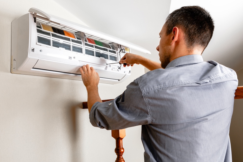 Male technician cleaning air conditioner indoors